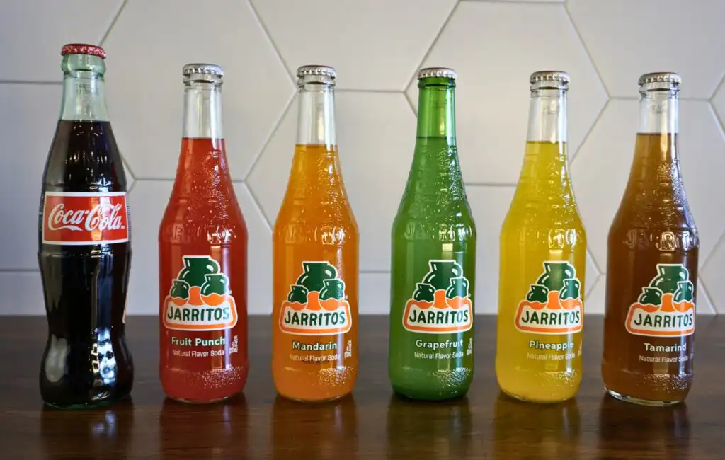 A row of six colorful soda bottles arranged neatly on a table.