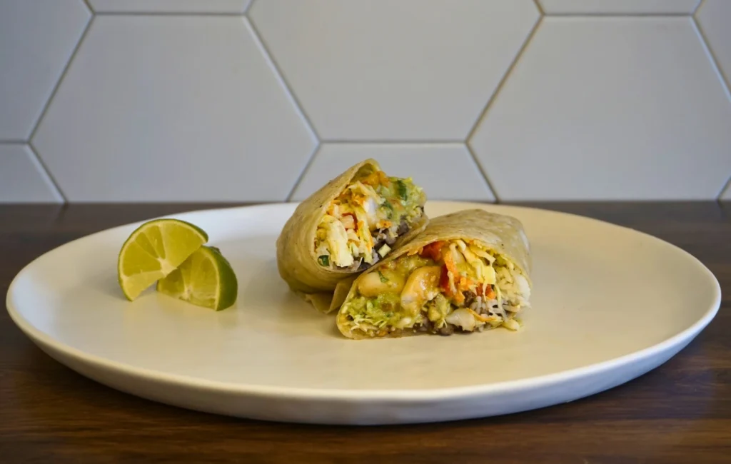 A wrap placed on a plate, accompanied by a slice of lime for garnish.