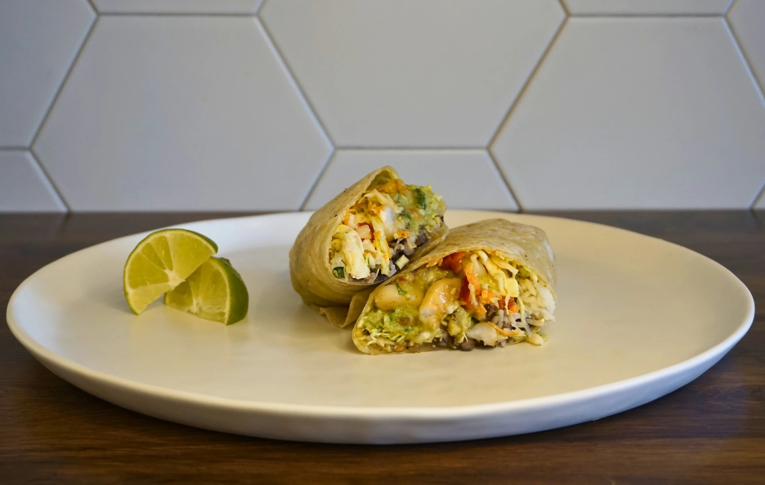 A wrap placed on a plate, accompanied by a slice of lime for garnish.