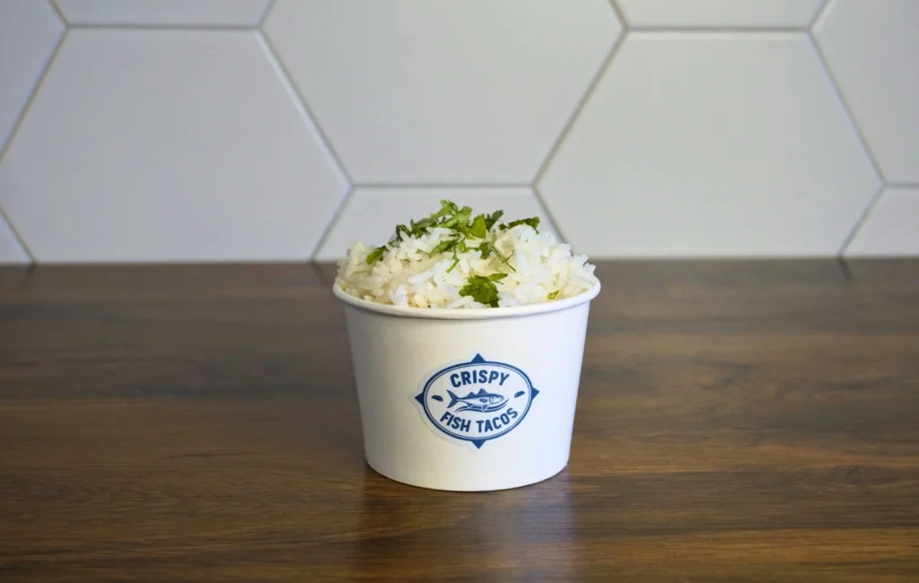 A white cup filled with rice, garnished with fresh herbs on top.