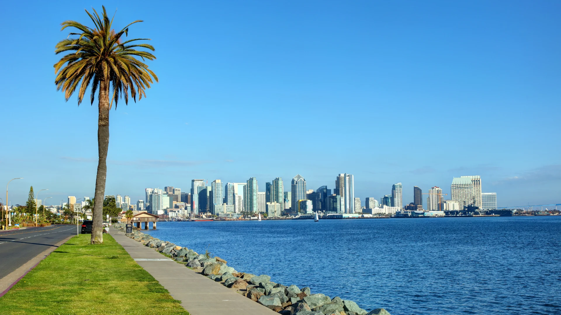 San Diego, California skyline viewed from a sandy beach under a clear blue sky.